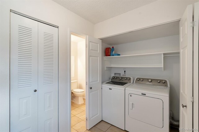 3407 S Ammons St Unit 20-2, Lakewood, CO 80227 - laundry area with washing machine and clothes dryer, light tile patterned floors, and a textured ceiling