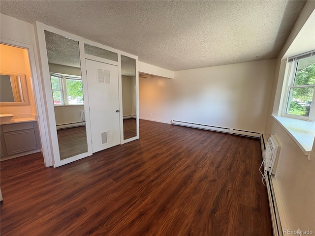 6905 Mariposa St Unit B, Denver, CO 80221 - unfurnished bedroom with a baseboard radiator, a textured ceiling, dark wood-style floors, baseboard heating, and multiple windows