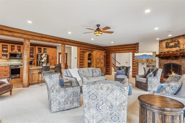 living area featuring recessed lighting, rustic walls, light carpet, ceiling fan, and a stone fireplace