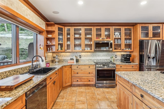 kitchen featuring light tile patterned floors, stainless steel appliances, decorative backsplash, a sink, and light stone countertops