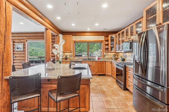 kitchen featuring recessed lighting, stainless steel appliances, a sink, light stone countertops, and a center island with sink