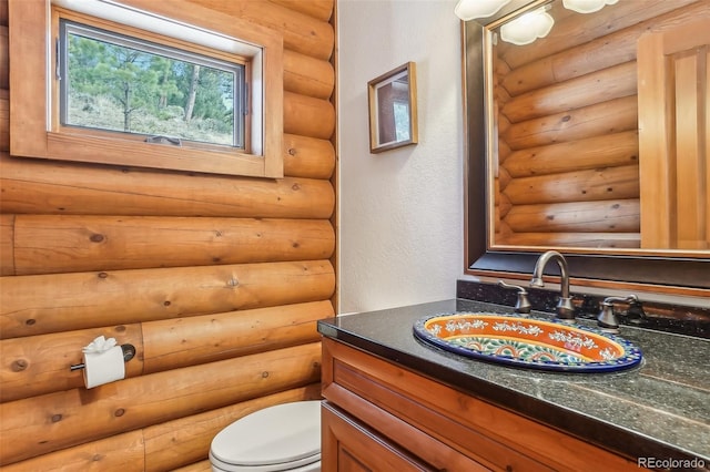 bathroom featuring toilet, log walls, and vanity