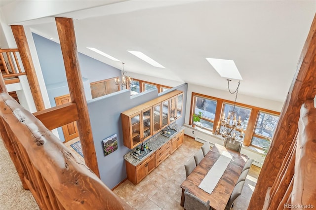 living area featuring a wealth of natural light, vaulted ceiling with skylight, and a notable chandelier