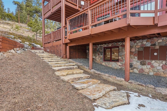 view of side of home featuring a deck, stone siding, and stairway