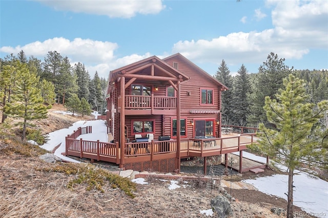 back of house featuring a balcony and a wooden deck