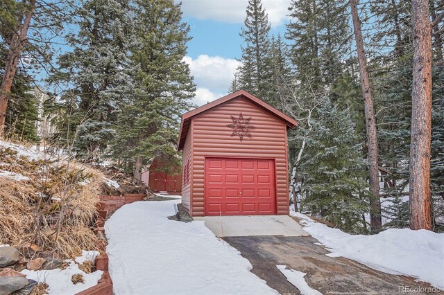 snow covered garage featuring a shed