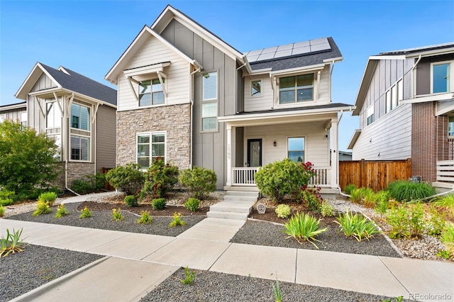 10295 E 59th Ave, Denver, CO 80238 - view of front facade with board and batten siding, stone siding, a porch, and roof mounted solar panels