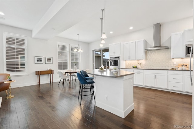 10295 E 59th Ave, Denver, CO 80238 - kitchen with wall chimney range hood, stainless steel appliances, recessed lighting, decorative backsplash, and an island with sink
