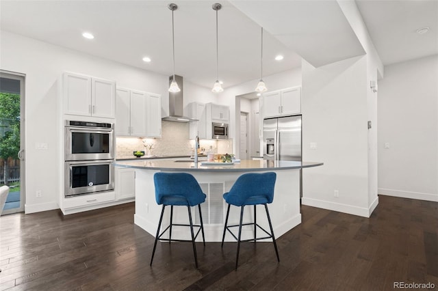 10295 E 59th Ave, Denver, CO 80238 - kitchen with wall chimney range hood, stainless steel appliances, a kitchen bar, tasteful backsplash, and a kitchen island with sink