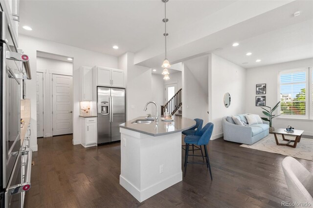 10295 E 59th Ave, Denver, CO 80238 - kitchen with stainless steel fridge, dark wood-style floors, a kitchen bar, open floor plan, and white cabinets