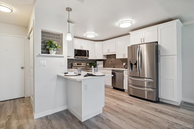 kitchen featuring white cabinetry, stainless steel appliances, decorative backsplash, and pendant lighting