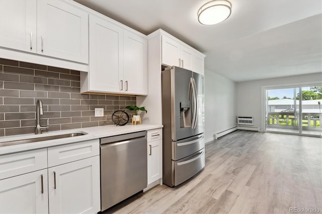 kitchen featuring stainless steel appliances, light hardwood / wood-style floors, sink, backsplash, and white cabinets