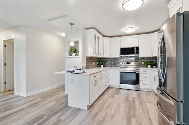 kitchen with appliances with stainless steel finishes, light hardwood / wood-style flooring, pendant lighting, and white cabinets