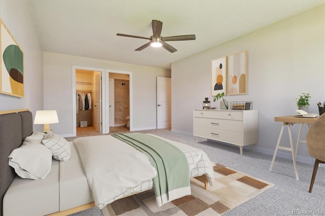 bedroom with light carpet, ensuite bath, a closet, ceiling fan, and a spacious closet