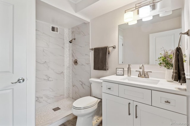 bathroom with vanity, a tile shower, and toilet