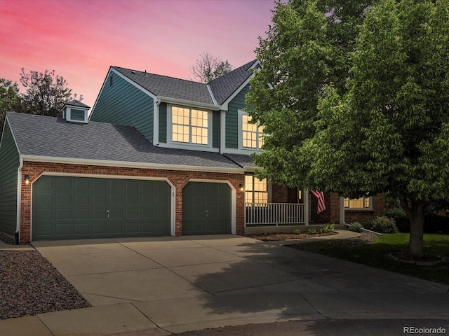 8953 W Brandt Pl, Littleton, CO 80123 - view of front of property with brick siding, concrete driveway, roof with shingles, and a porch