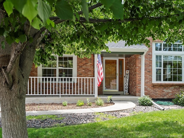8953 W Brandt Pl, Littleton, CO 80123 - entrance to property featuring brick siding, covered porch, and a shingled roof