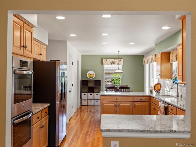 8953 W Brandt Pl, Littleton, CO 80123 - kitchen featuring stainless steel appliances, a peninsula, light wood-style floors, light stone counters, and recessed lighting