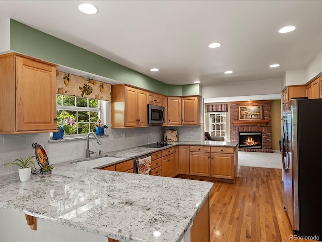 8953 W Brandt Pl, Littleton, CO 80123 - kitchen with stainless steel appliances, a peninsula, a brick fireplace, decorative backsplash, and recessed lighting