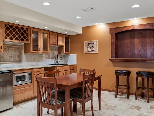 8953 W Brandt Pl, Littleton, CO 80123 - kitchen with stainless steel microwave, refrigerator, brown cabinets, recessed lighting, and backsplash