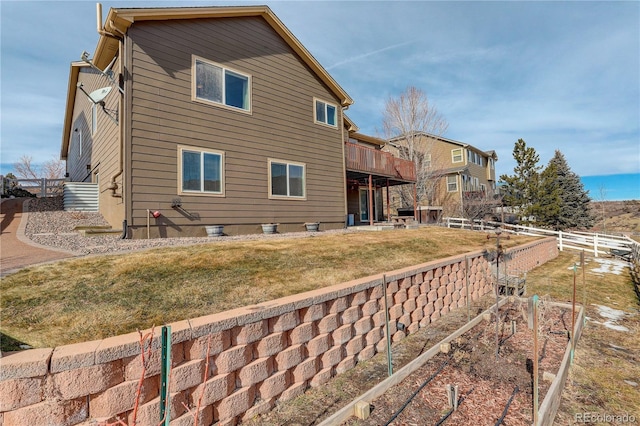 back of property featuring a lawn and a deck