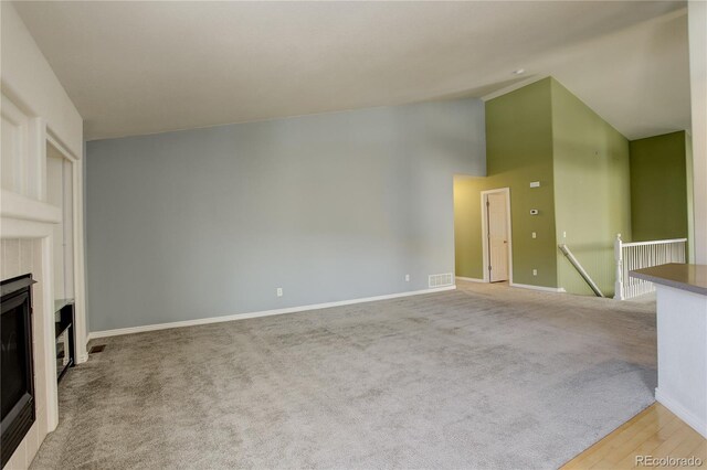 unfurnished living room with light colored carpet and high vaulted ceiling