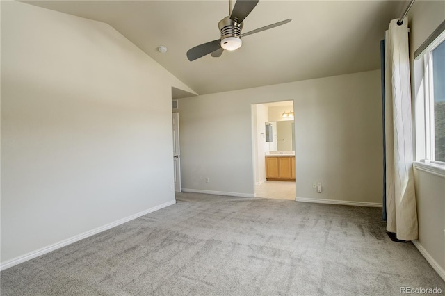 unfurnished bedroom featuring ceiling fan, lofted ceiling, connected bathroom, and light carpet