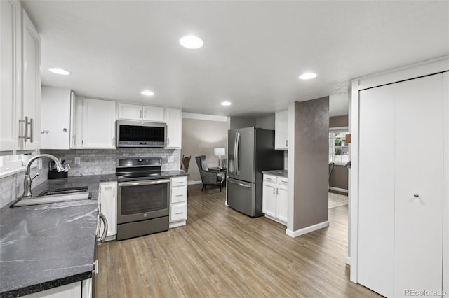 6514 Zinnia St, Arvada, CO 80004 - kitchen featuring stainless steel appliances, white cabinets, light wood-type flooring, decorative backsplash, and recessed lighting
