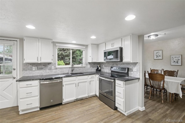 6514 Zinnia St, Arvada, CO 80004 - kitchen featuring appliances with stainless steel finishes, dark countertops, decorative backsplash, light wood-type flooring, and recessed lighting