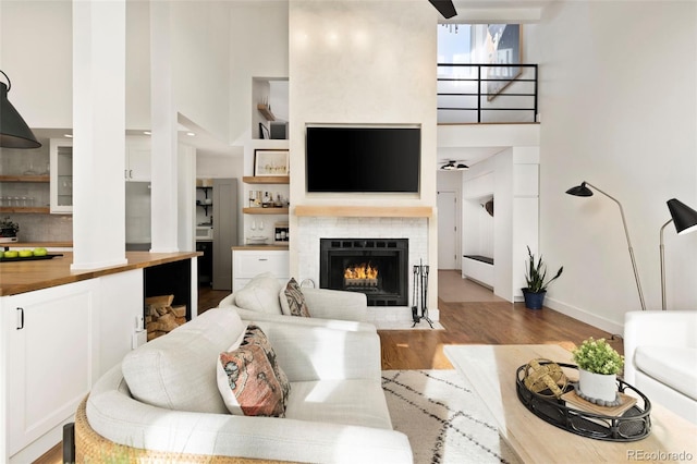 living room featuring a high ceiling, a tile fireplace, and light hardwood / wood-style flooring