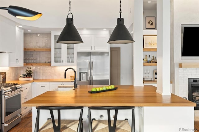 kitchen featuring stainless steel appliances, hanging light fixtures, and white cabinets