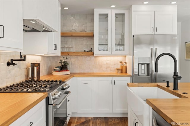 kitchen featuring white cabinetry, wood counters, stainless steel appliances, and backsplash