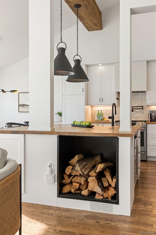 kitchen with white cabinetry, tasteful backsplash, hanging light fixtures, hardwood / wood-style flooring, and high end stove