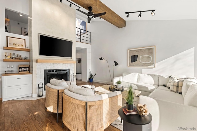 living room featuring beamed ceiling, ceiling fan, dark wood-type flooring, and a fireplace