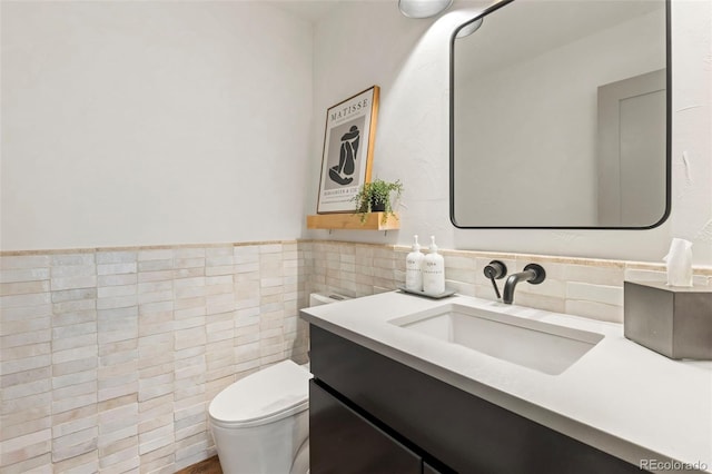 bathroom with tile walls, vanity, and toilet