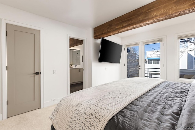 bedroom with beamed ceiling, access to outside, light colored carpet, and ensuite bath