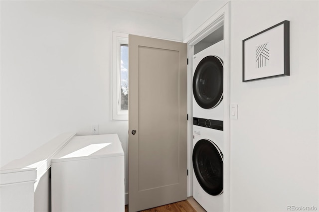 clothes washing area featuring stacked washer and clothes dryer and hardwood / wood-style floors