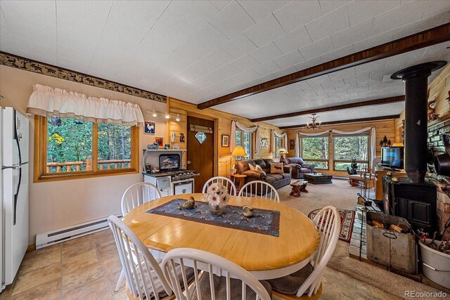 3938 County Road 60, Grant, CO 80448 - dining area with a wood stove, a baseboard heating unit, baseboards, and beamed ceiling