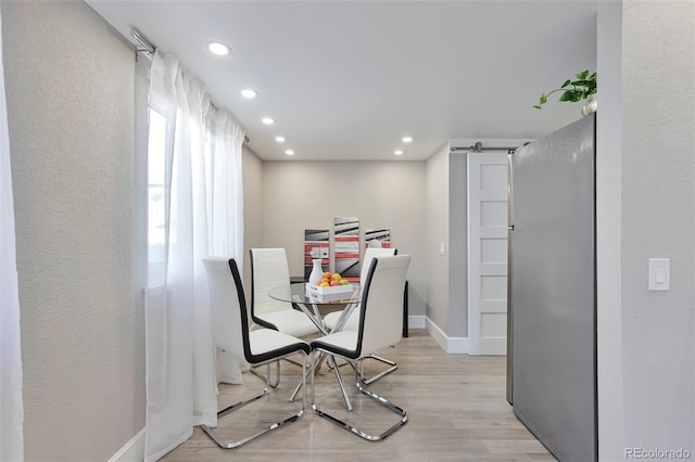 dining space with a barn door and light hardwood / wood-style floors