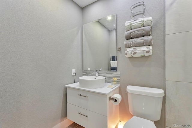 bathroom featuring decorative backsplash, toilet, and vanity