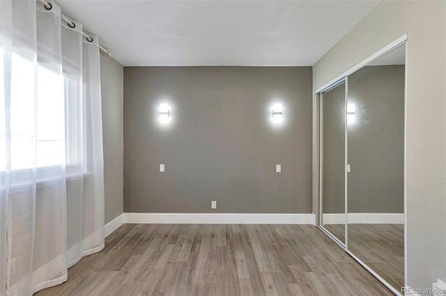 unfurnished bedroom with a closet and light wood-type flooring