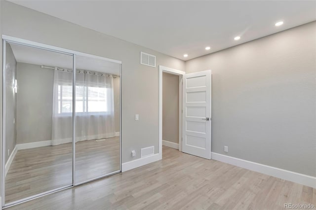 unfurnished bedroom featuring light wood-type flooring and a closet