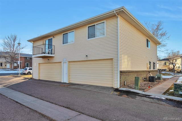 view of property exterior with central AC, a balcony, and a garage