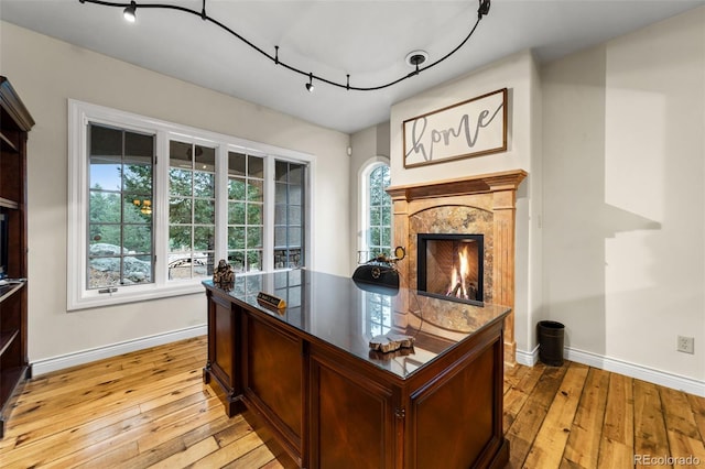 office area with a high end fireplace and light hardwood / wood-style floors