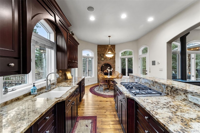 kitchen with stainless steel gas stovetop, decorative light fixtures, light wood-type flooring, and plenty of natural light