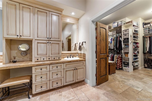 4450 Walker Rd, Colorado Springs, CO 80908 - bathroom with stone tile floors, vanity, a walk in closet, and backsplash