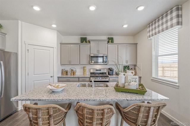 kitchen with stainless steel appliances, gray cabinets, a breakfast bar area, and sink