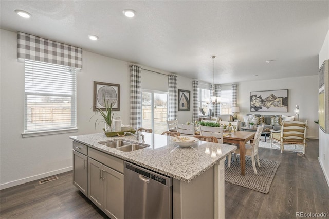 kitchen featuring sink, hanging light fixtures, stainless steel dishwasher, gray cabinets, and an island with sink