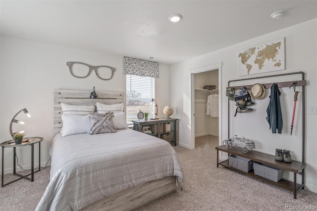 bedroom featuring light colored carpet, a spacious closet, and a closet