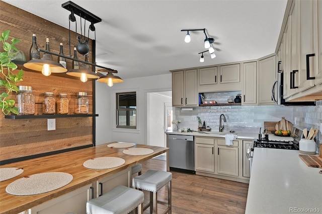 kitchen featuring hanging light fixtures, appliances with stainless steel finishes, gray cabinets, hardwood / wood-style floors, and decorative backsplash